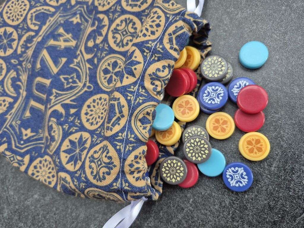 Runde, bunte Spielsteine fallen aus einem Beutel mitt Muster.