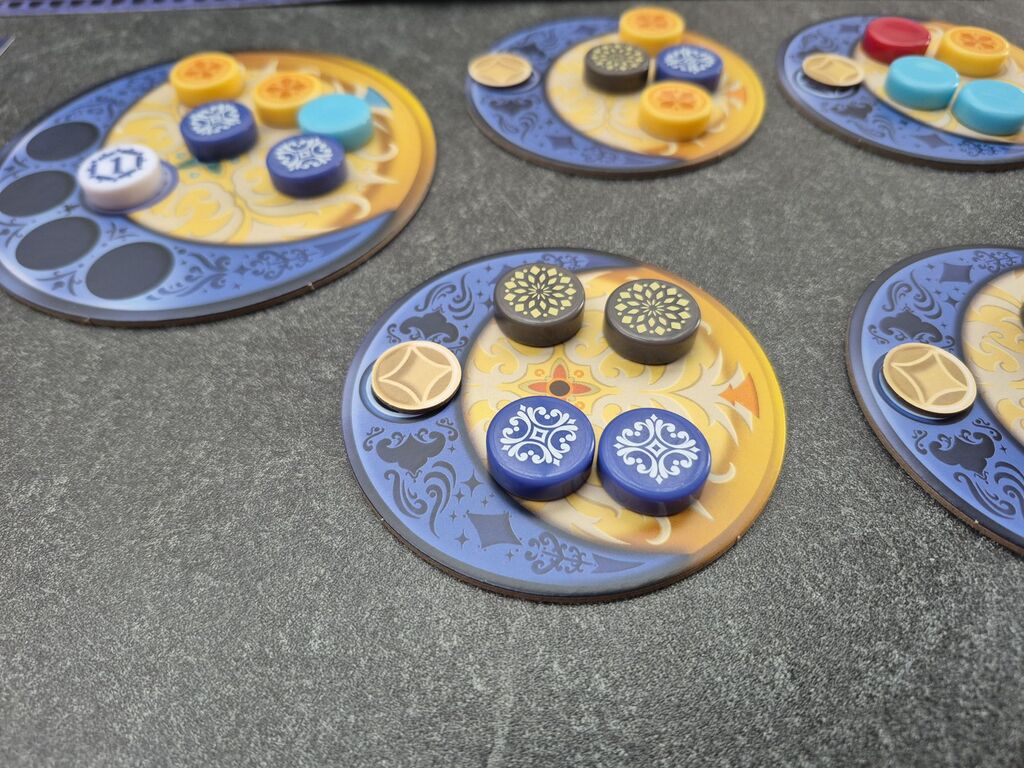 Auf einem Plättchen liegen vier runde Spielsteine.