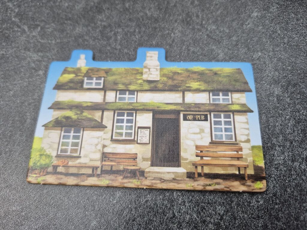 Ein Plättchen, das ein Haus zeigt, an dem ein Schild mit der Aufschrift "Old Pub" hängt.