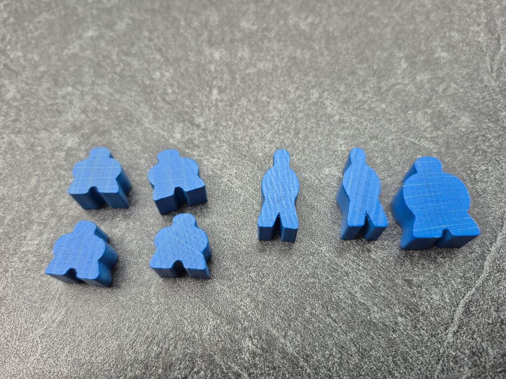 Sieben blaue Meeple in drei Größen.