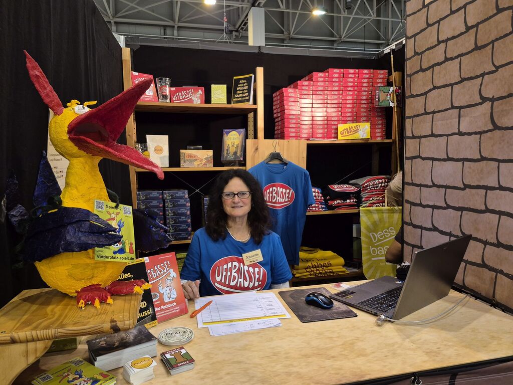 Eine Frau sitzt vor einem Regal mit Spielen und T-Shirts.