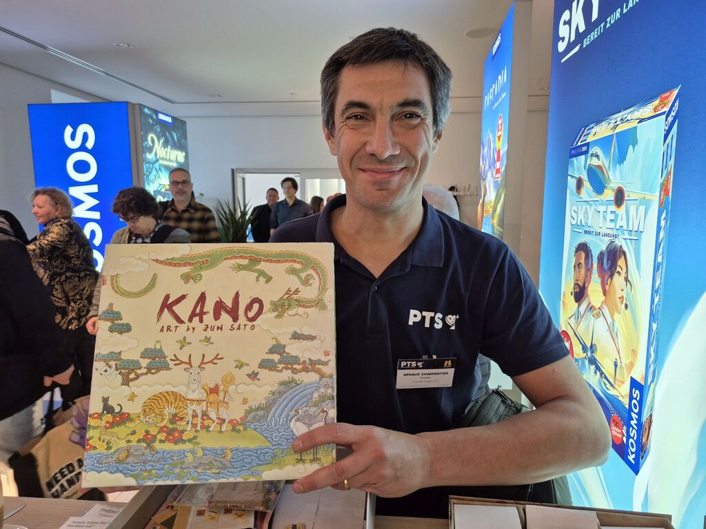 Ein Mann hält eine Spielschachtel hoch.