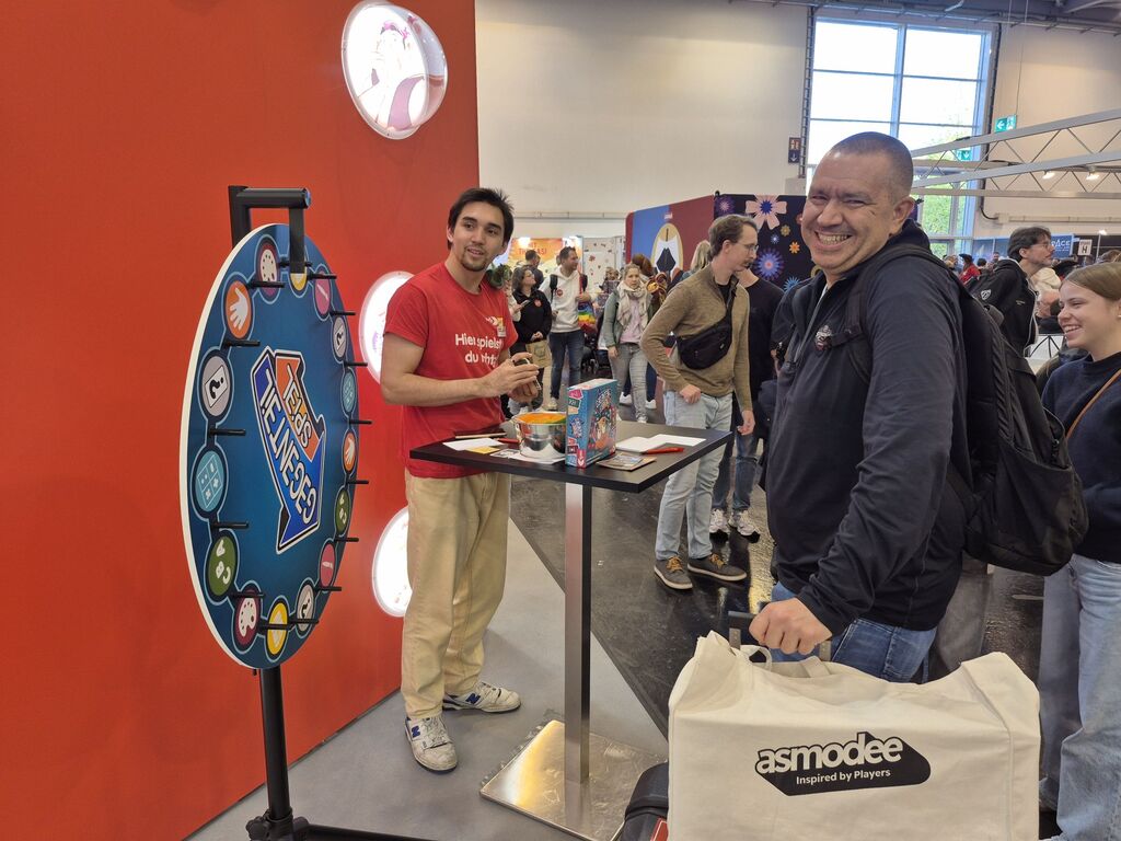 Ein Mann steht lachend vor einem Stand.