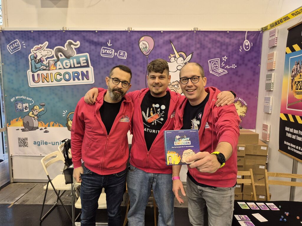 Drei Männer halten ein Spiel hoch.