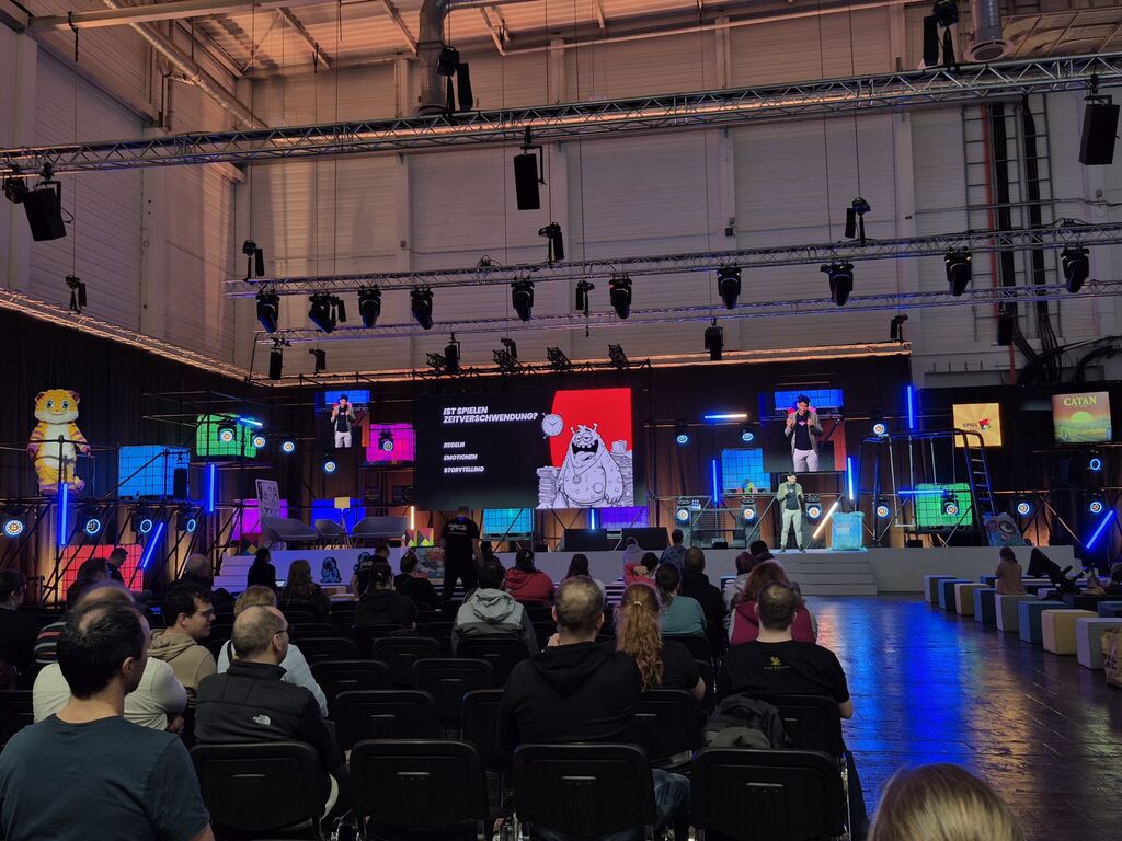 Eine Bühne, davor Stühle und Zuschauer.