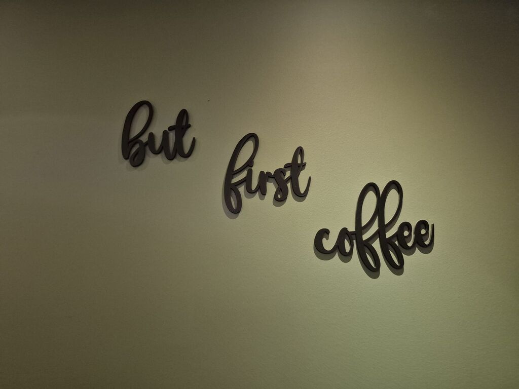 "But first coffee" als Schriftzug an einer Wand.