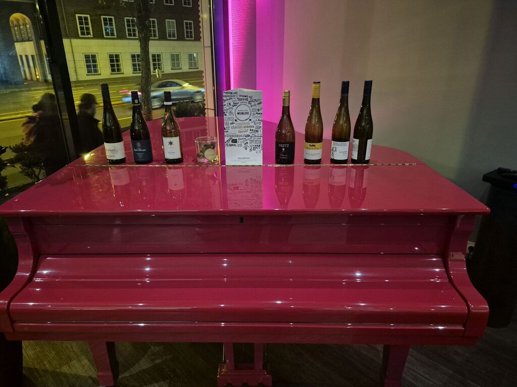 Ein rotes Klavier, darauf Weinflaschen.