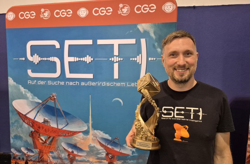 Ein Mann hält einen Pokal vor einer Werbewand für "Seti".