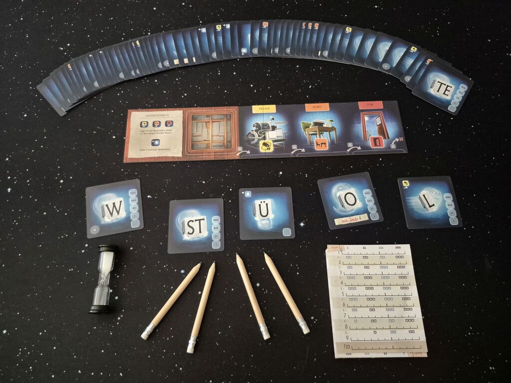 Das Spielmaterial von "Spukstaben" mit Karten, Stiften, Sanduhr und Block.