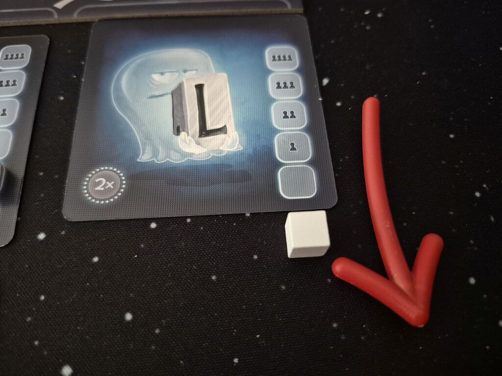 Eine Karte mit einem "L", darunter liegt ein weißer Würfel, daneben ein nach unten zeigender Pfeil.