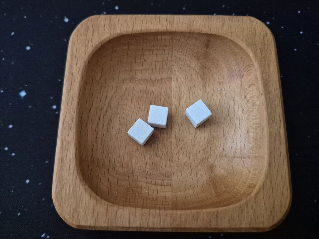 Drei Holzwürfel in einer Holzschale.