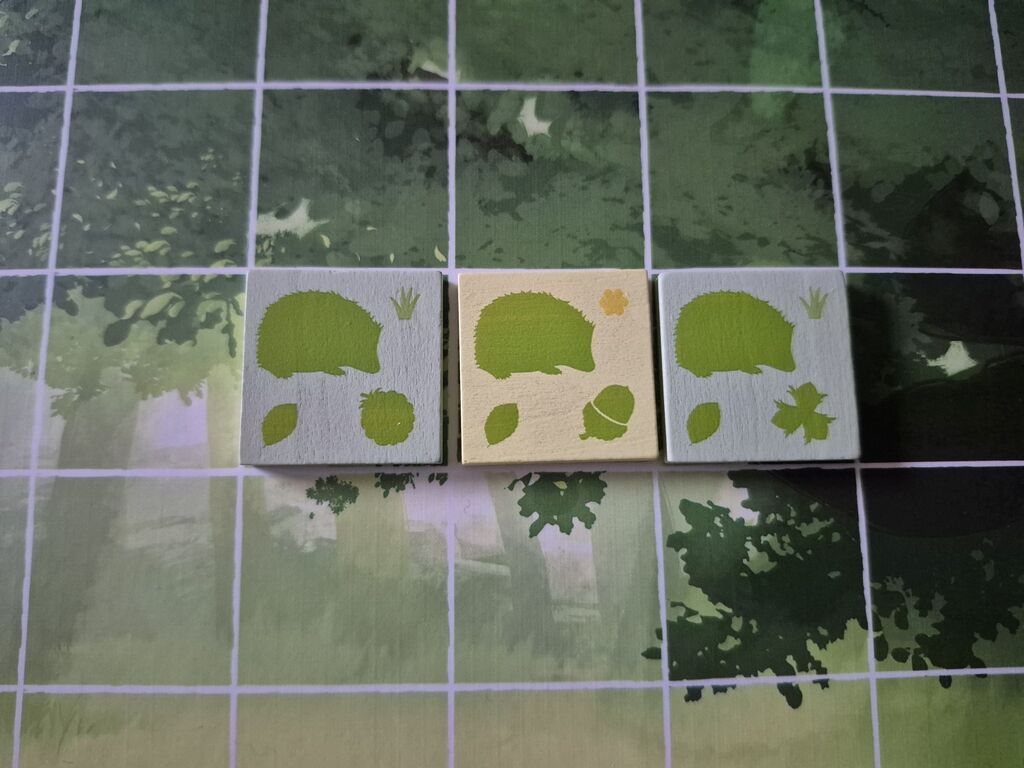 Drei Plättchen aus "The Glade" mit Igelsymbol auf dem Spielplan.