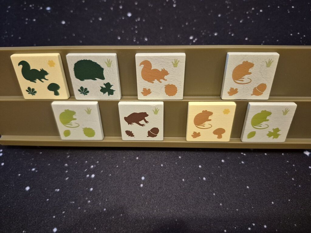 Acht Plättchen stehen in zwei Reihen auf einem Bänkchen.