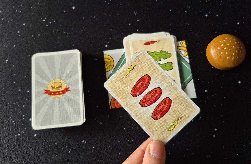 Eine Hand hälte eine Karte über das restliche Spielmaterial von "Burger Slam".