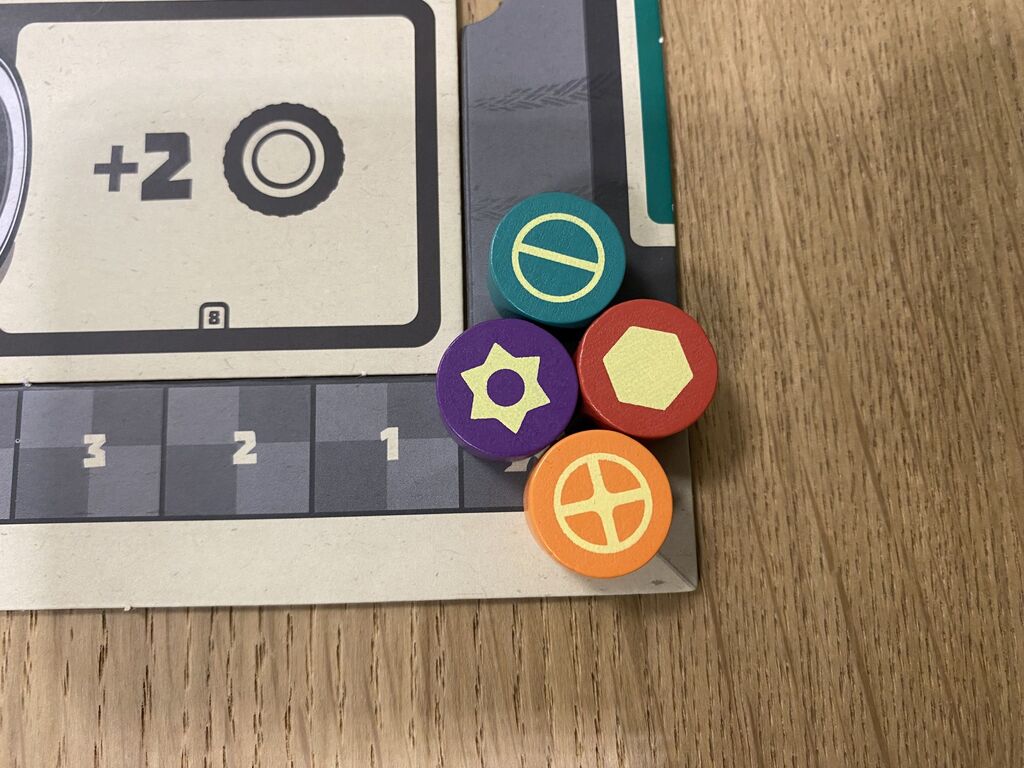 Vier Marker liegen am Beginn einer Zählleiste des Spielplans von "Grease Monkey Garage".