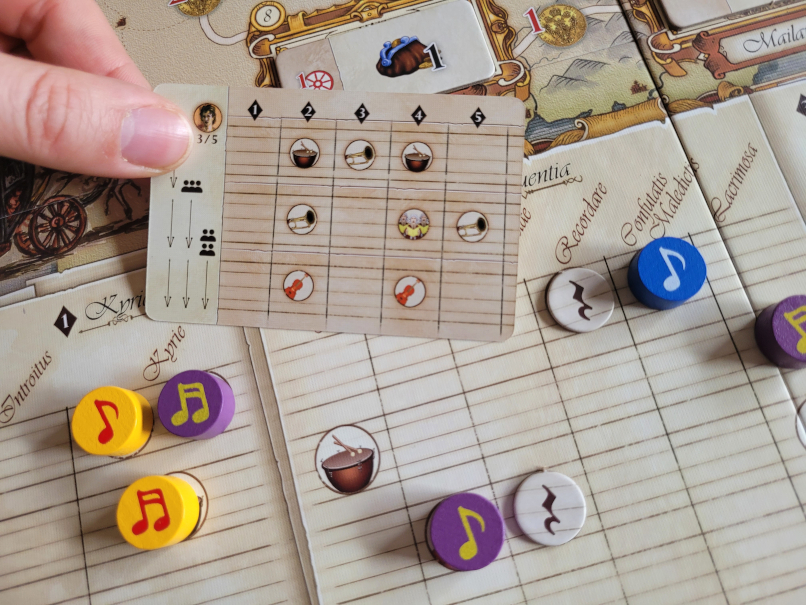 Eine Hand hält eine Karte über den Spielplan.