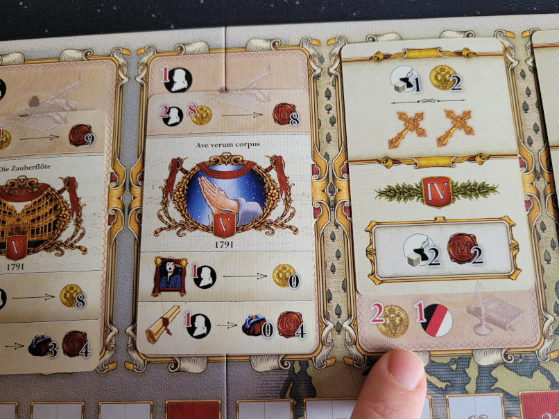 Ein Finger zeigt auf andere Symbole auf dem Spielplan von "Lacrimosa".