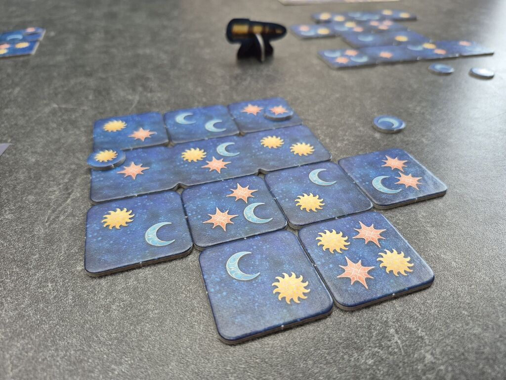 Plättchen liegen in einem Raster, im Hintergrund weitere Plättchen.