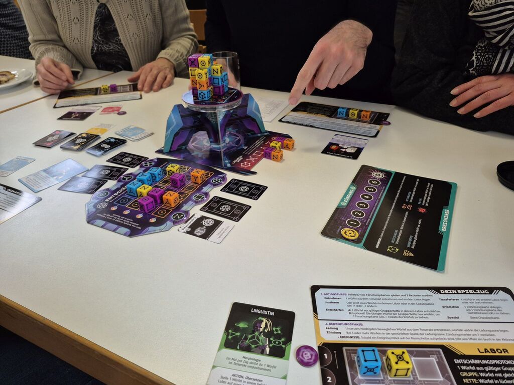 Spielmaterial und die Hände von mehreren Personen.