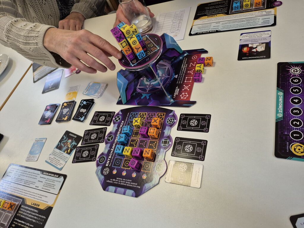 Eine Hand greift zum Spielmaterial.