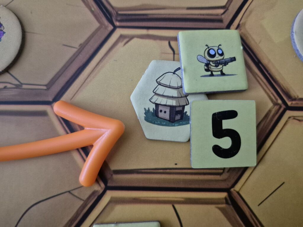 Ein Pfeil zeigt auf drei Marker auf einem Feld des Spielplans.