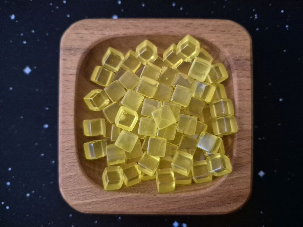 Eine Holzschale mit kleinen, gelben Kunststoffwürfeln.