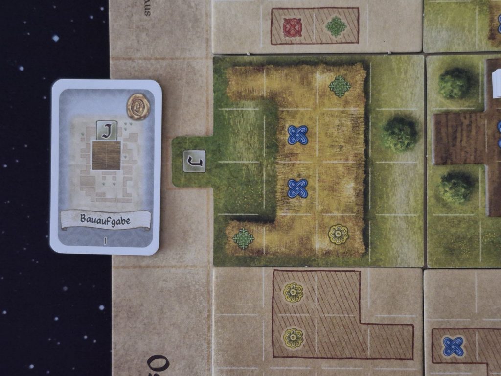 Eine Karte neben einem Spielplanteil mit umgedrehtem Planteil.