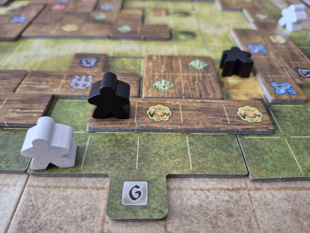 Drei Spielfiguren auf dem Spielplan von "Campus Galli".