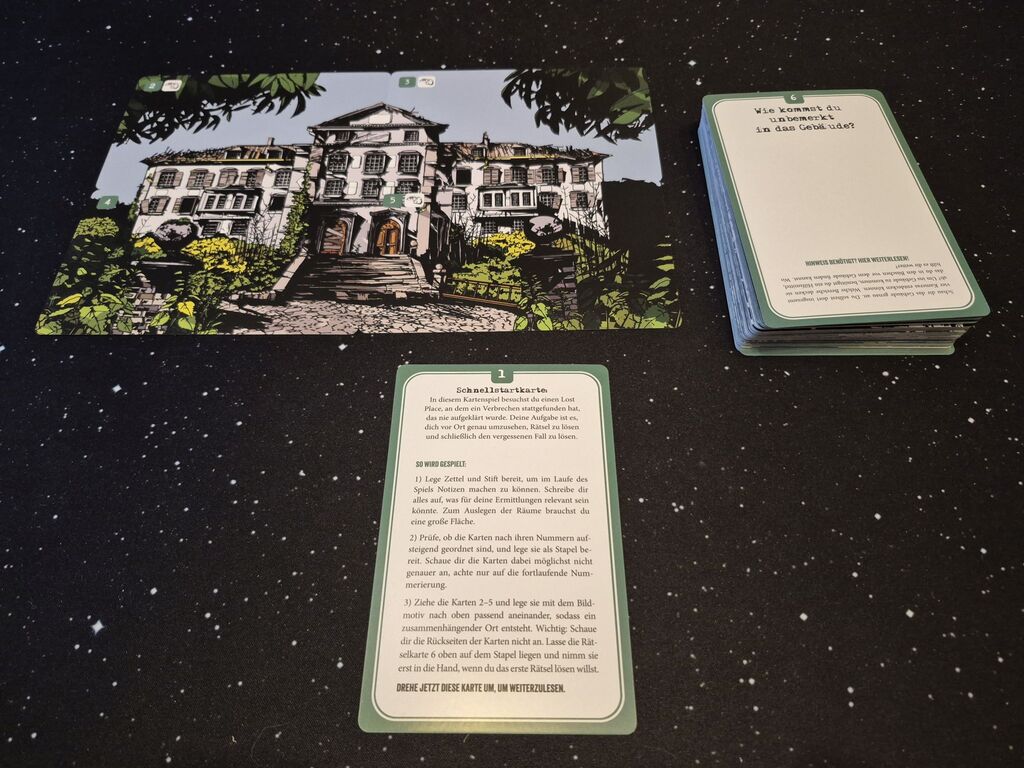 Ein Bild aus Karten von einem zerfallenen alten Gebäude. Daneben ein Kartenstapel und eine Karte mit Text.