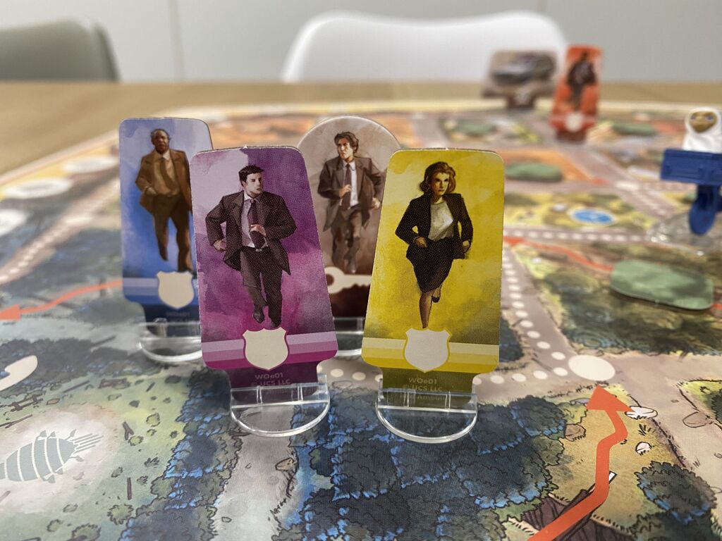 Vier Spielfiguren, drei Männer im Anzug und eine Frau im schwarzen Kostüm.