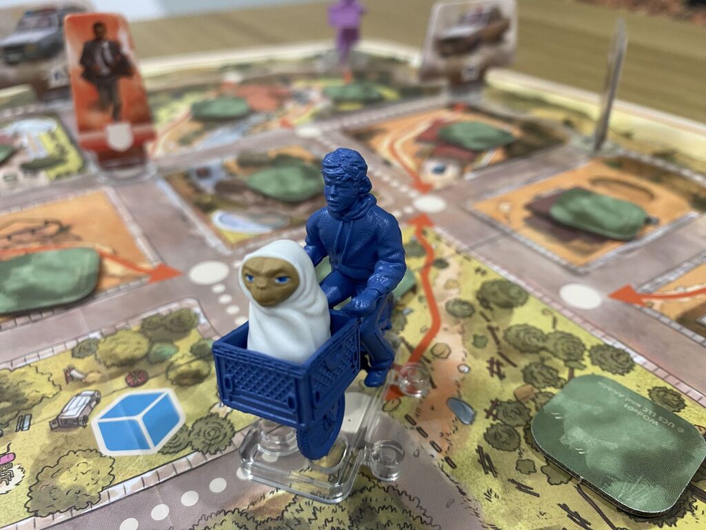 Eine Spielfigur in Form eines Kindes auf einem Fahrrad. Im Korb sitzt E.T.