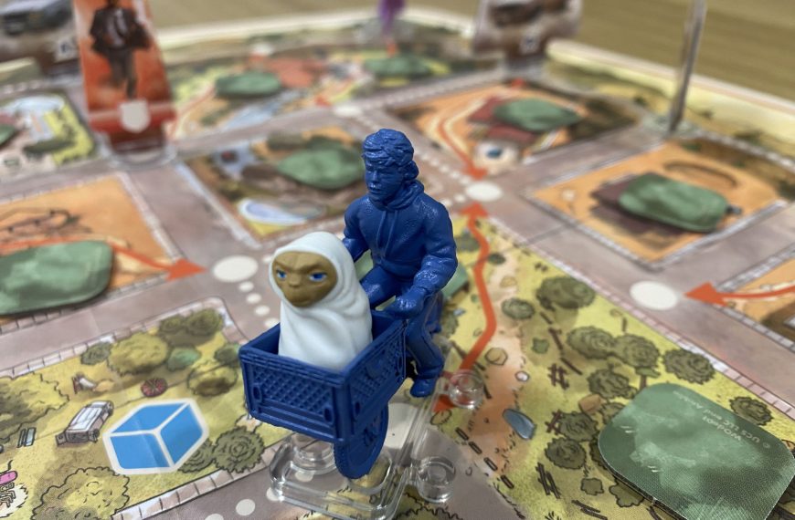 Eine Spielfigur in Form eines Kindes auf einem Fahrrad. Im Korb sitzt E.T.