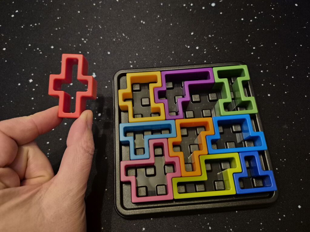 Eine Hand hält ein Teil neben das restliche Spielmaterial.