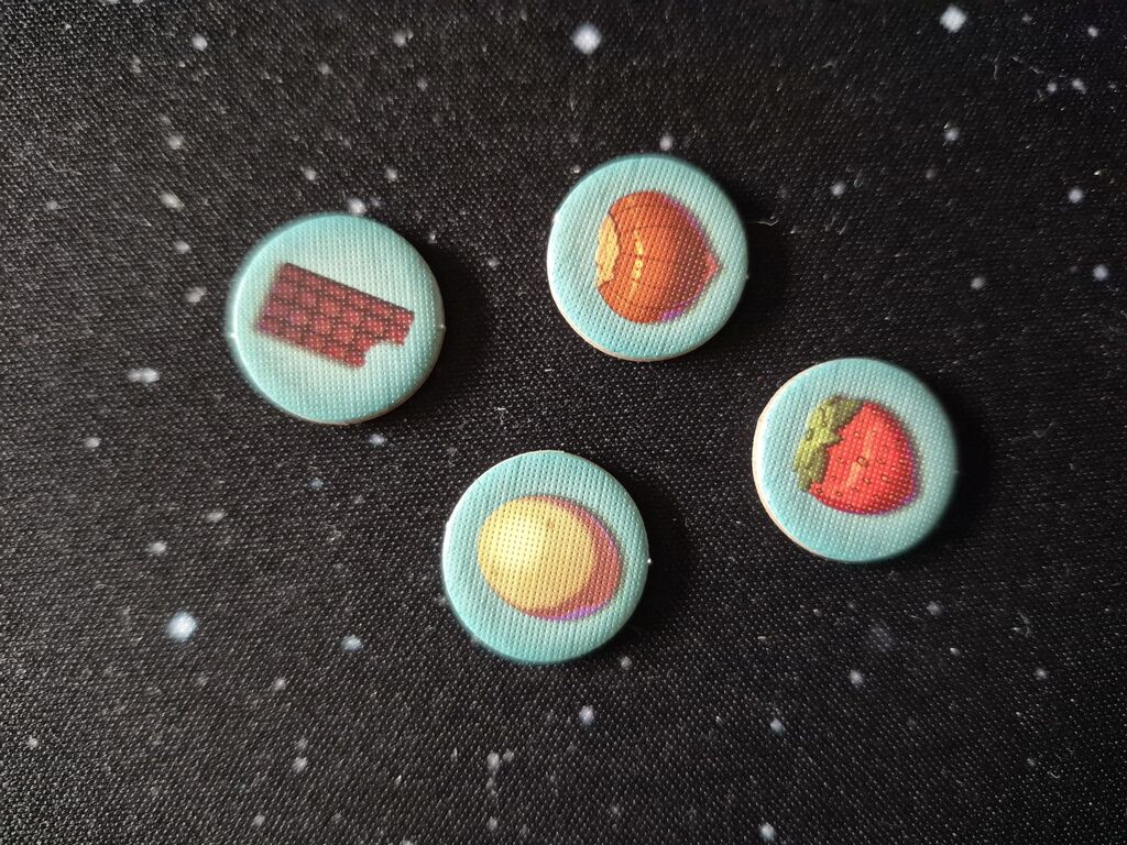 Vier Marker mit Schokolade, Haselnuss, Erdbeere und etwas, das Ei, Kartoffel oder Marzipan sein könnte.