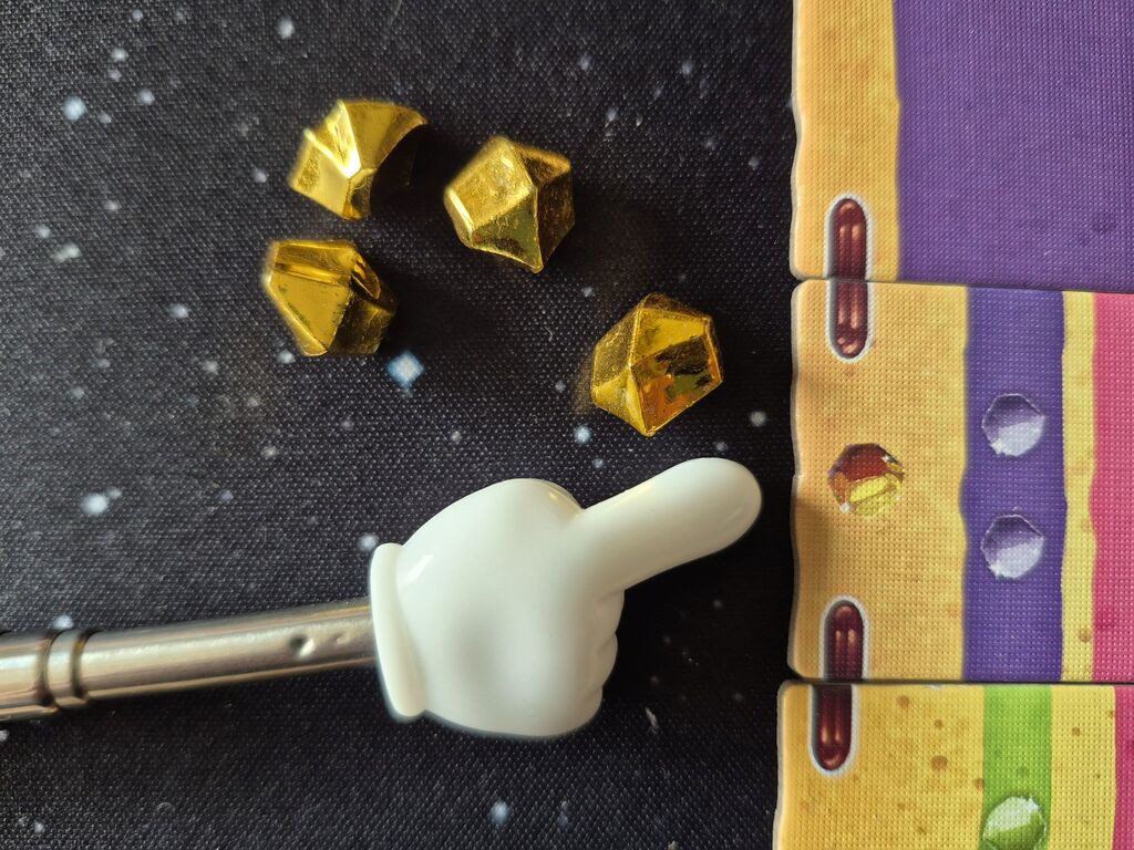 Ein Zeiger liegt neben einem goldenen Punkt. Daneben vier goldene Zuckerstücke.