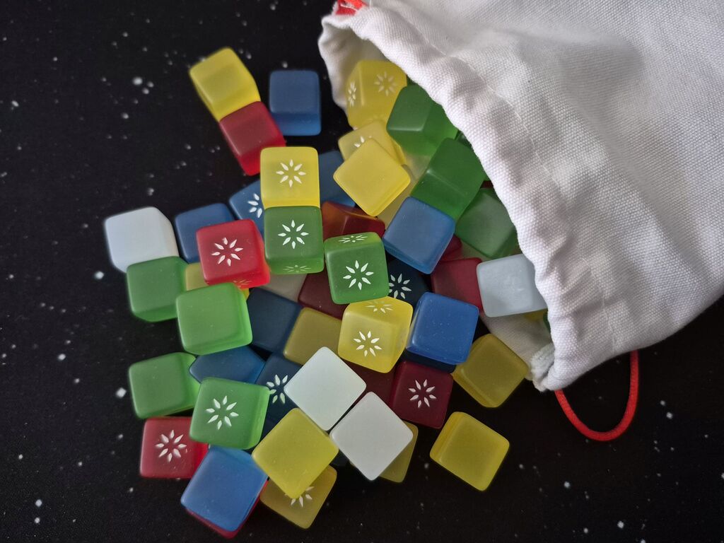 Bunte Würfel mit und ohne Symbole fallen aus einem Stoffbeutel.