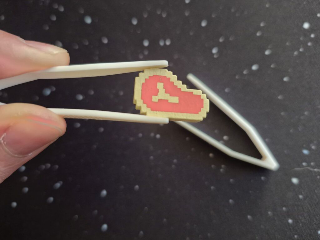 Eine Hand hält eine Pinzette mit einem Steak-Marker.