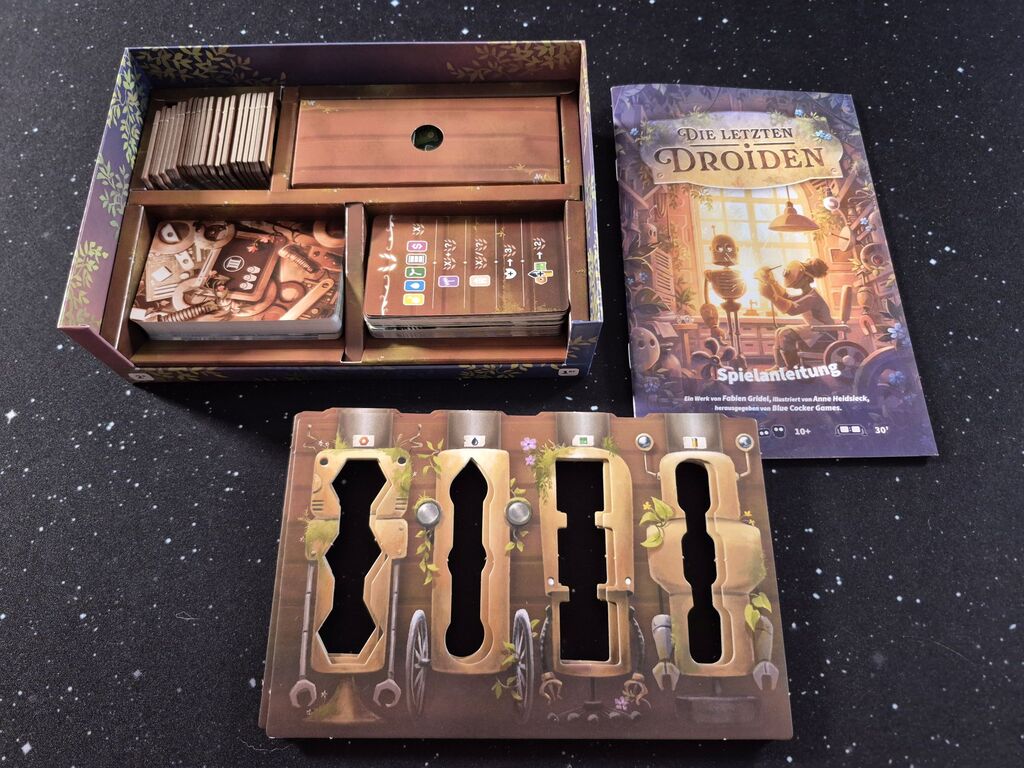 Das Spielmaterial von "Die letzten Droiden" mit Schachtel und Anleitung.