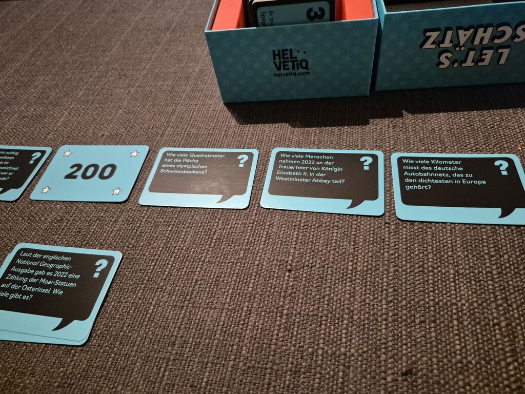 Karten liegen vor der Spielschachtel in einer Reihe.