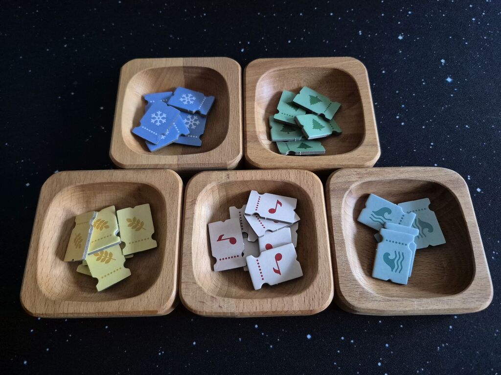 Fünf verschiedene Plättchen in Ticket-Form in Holzschalen.