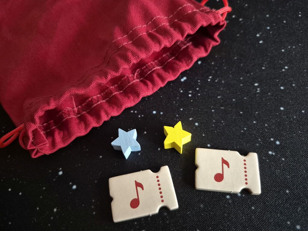 Zwei Chips mit einer Note und zwei Sterne liegen vor dem Stoffbeutel.