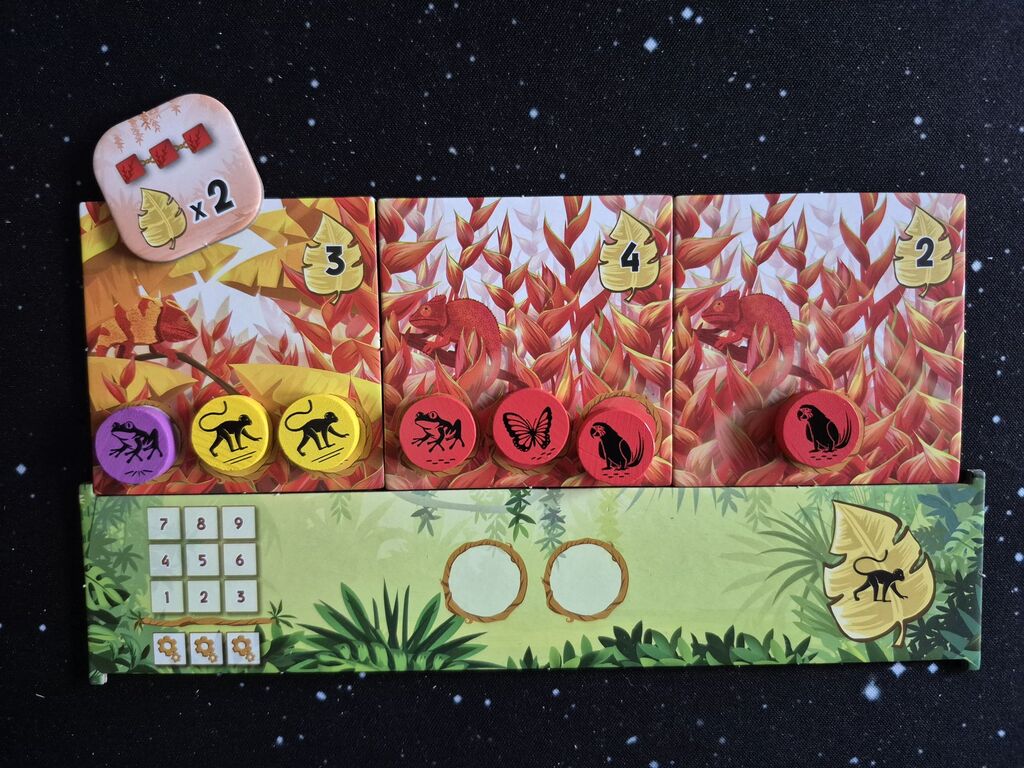 Drei quadratische Plättchen in einer Reihe, darauf verschiedenfarbige Marker und ein kleines Plättchen.