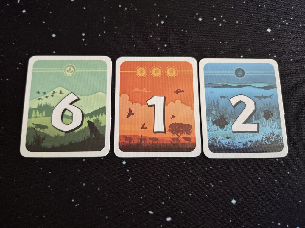 Drei Karten nebeneinander mit Zahlen und Symbolen.