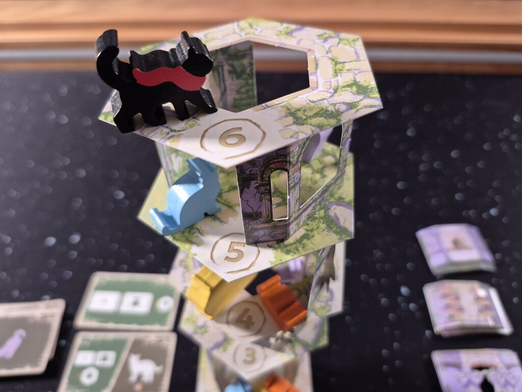 Katzenfiguren stehen auf verschiedenen Turmstockwerken.