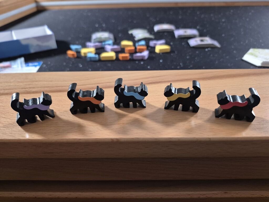 Fünf schwarze Katzen-Figuren mit buntem Schal.