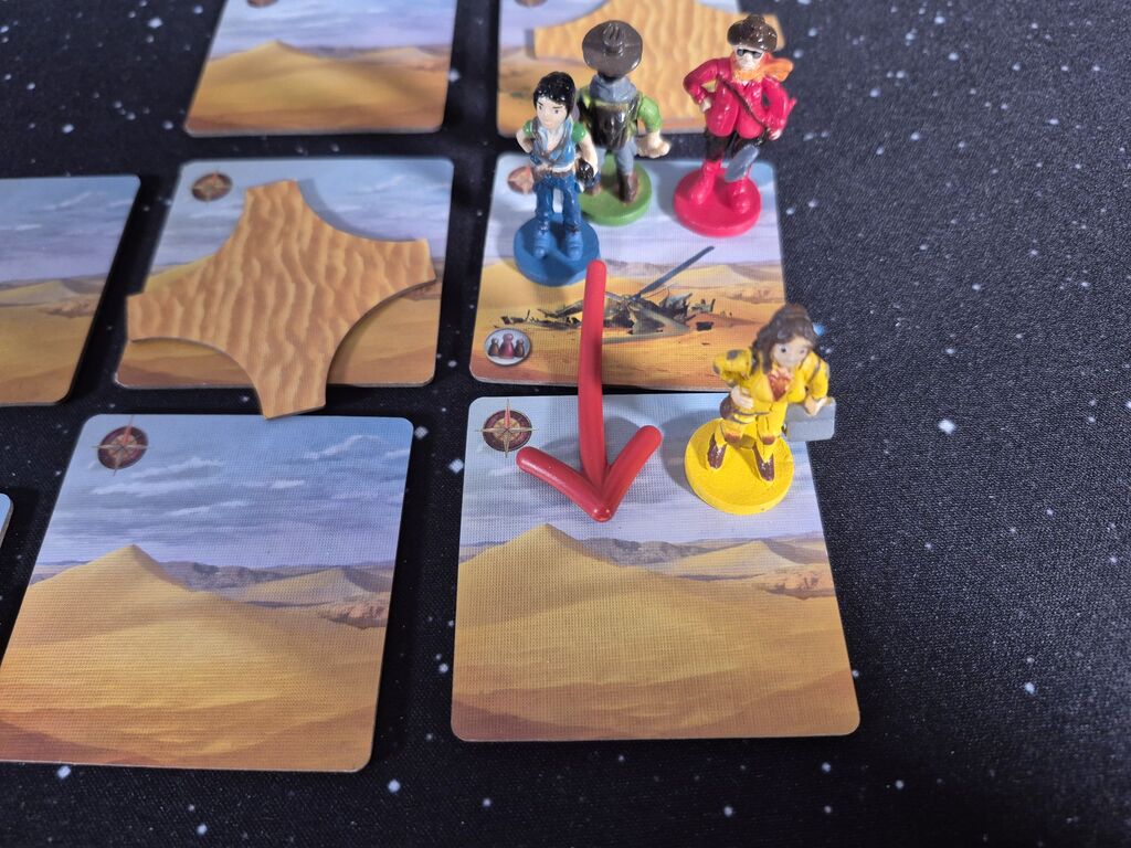 Vier Spielfiguren aus "Forbidden Desert" auf einem Teil des Spielplans.