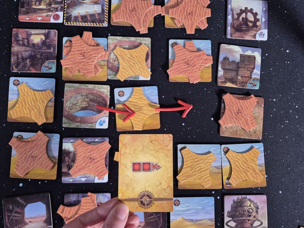 Spielplan aus Feldern mit Sandplättchen.