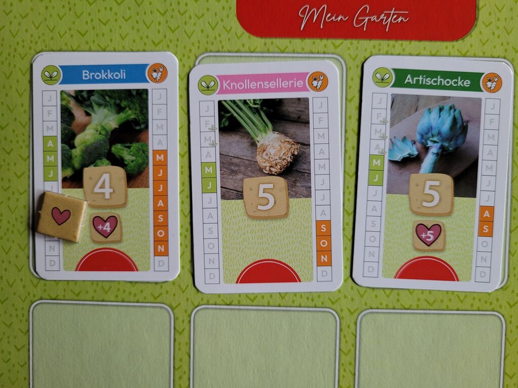 Drei Karten aus "Homefarming" auf dem Spielertableau. Je einmal Brokkoli, Knollensellerie und Artischocke.