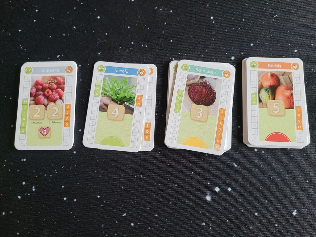 Vier Kartenstapel mit Obst und Gemüse, Zahlen und Symbolen.