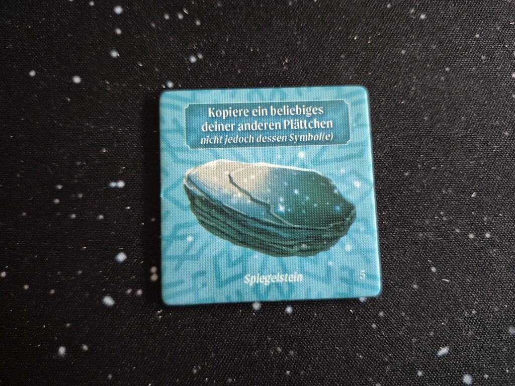 Ein Plättchen mit einem glänzenden Stein und Text.